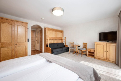 Vierbettzimmer mit Balkon im Hotel Stegerbräu in Radstadt mit Couchbett und zusätzlicher Schlafmöglichkeit als Stockbett, Wohnbeispiel – Ausstattung kann variieren.