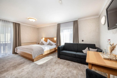 Vierbettzimmer mit Balkon im Hotel Stegerbräu in Radstadt mit Doppelbett, Couch und Sitzbereich. Wohnbeispiel - Ausstattung kann variieren.