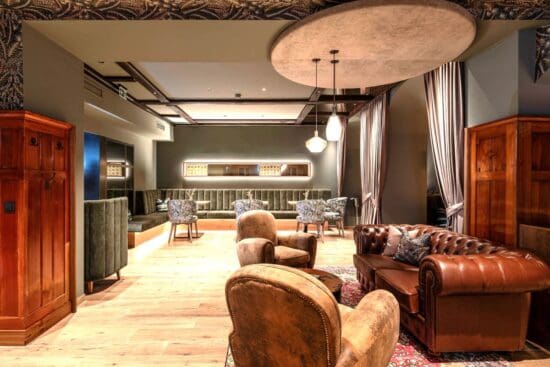 Aufenthaltsraum-Julies©Hotel-Stegerbrau-Radstadt_0066 Julie's Wohnzimmer mit Leder-Loungegarnitur und Frühstücksbereich mit grün gepolsterter Sitzbank, Sesseln und Holztischen