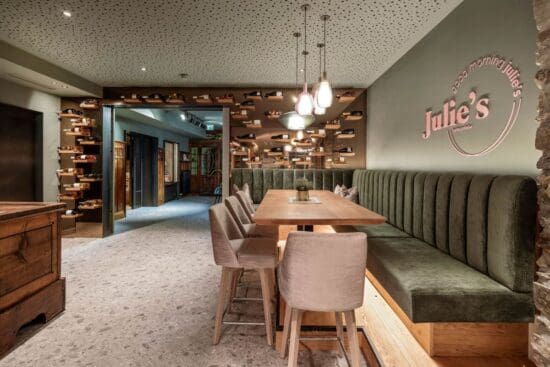 Julies-Fruehstuecks-Treff-Radstadt©Stegerbraeu_0010 Stammtisch-Ecke von Julie's Frühstück-Restaurant - Holztisch mit Hochstühlen, grün gepolsteter Eckbank und Weinregalen
