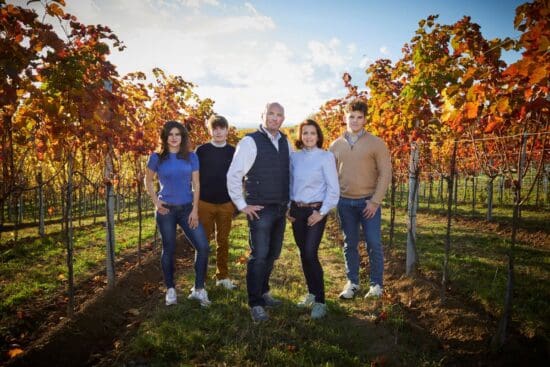 Weingut-Schmidt-Familie Familie Schmidt vom Weingut Schmidt in Niederösterreich steht gemeinsam zwischen den herbstlich gefärbten Rebzeilen ihres Weinguts.