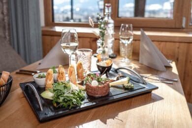 Beef Tartar im Restaurant Stegerbräu Kreativ angerichtetes Beef Tartar mit Salat, knusprigem Gebäck und Beilagen auf einer schwarzen Platte im Restaurang Stegerbräu in Radstadt