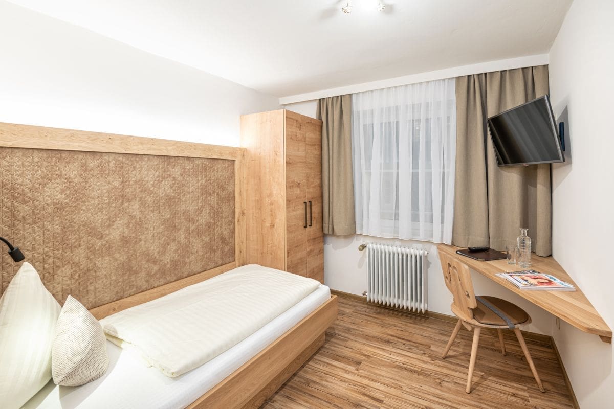 Einbettzimmer, schlicht-elegante Einrichtung mit Holzelementen, Einzelbett, Schreibablage, Stuhl, Schrank, Kabel-TV, Vinylboden