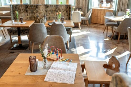 Kinderfreundlich essen im Restaurant Stegerbräu - Radstadt Kindertisch im Restaurant Stegerbräu in Radstadt mit Hochstuhl, Malbuch, Buntstiften und Holzspielzeug.
