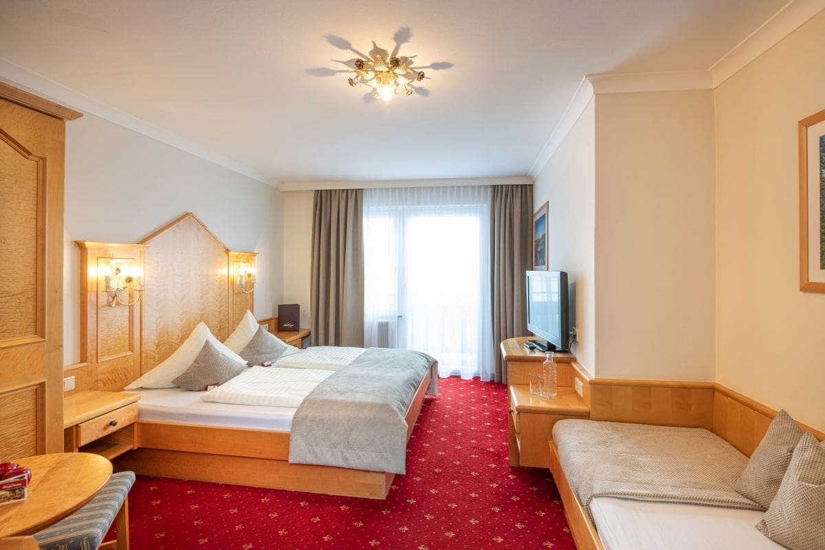 Ansicht eines Dreibettzimmers im Haupthaus, eingerichtet in heller Buche, Teppichboden, Doppelbett und extra 3.Bett, neues Badezimmer