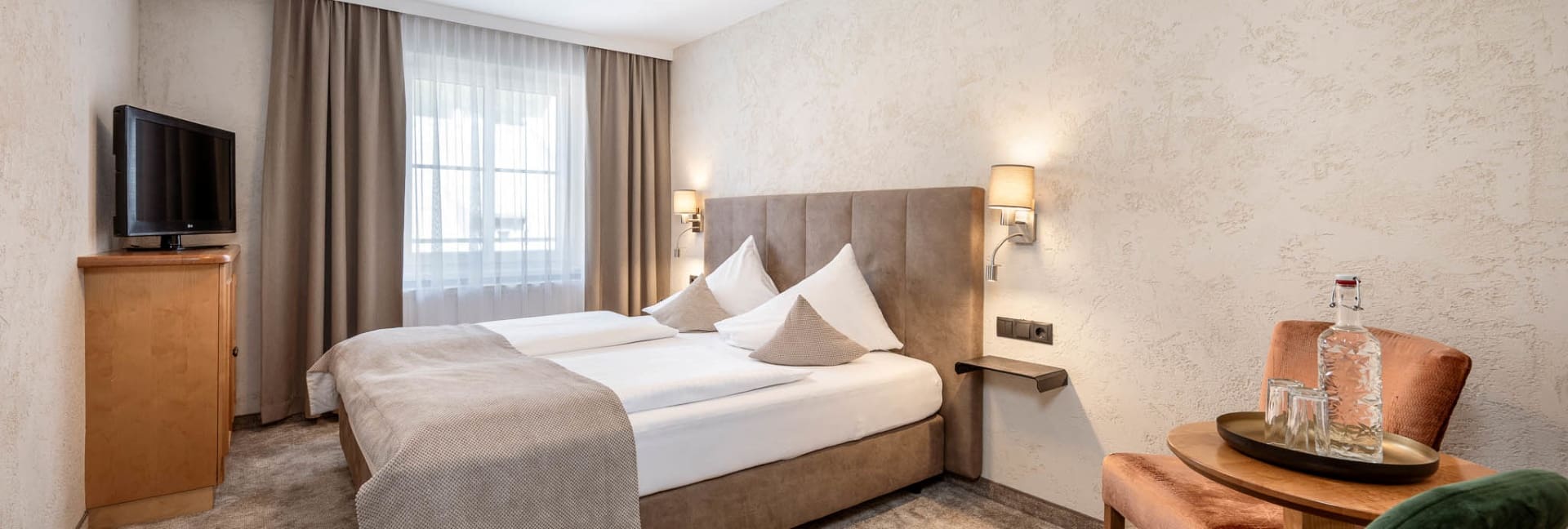 Komfortable Zimmer im Hotel Stegerbräu in Radstadt mit Doppelbett, Sitzbereich und heller Einrichtung